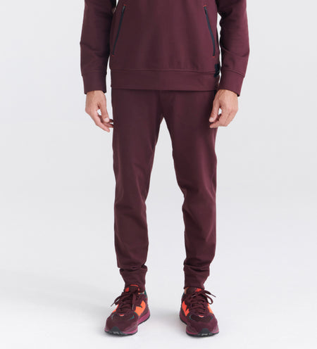 Man wearing maroon joggers and hoodie with red sneakers
