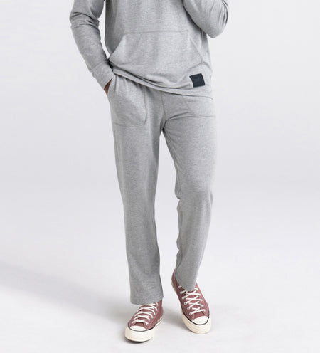 Man wearing light gray hoodie and lounge pants with red sneakers