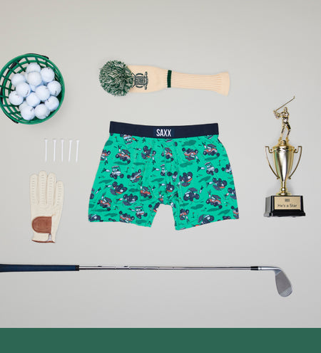  Green patterned boxer brief surrounded by golf equipment such as club tees and balls